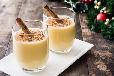 Tarçın ahşap masa üzerinde ev yapımı yumurta likörü. Tipik Noel tatlısı.
