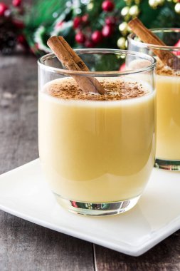 Tarçın ahşap masa üzerinde ev yapımı yumurta likörü. Tipik Noel tatlısı.