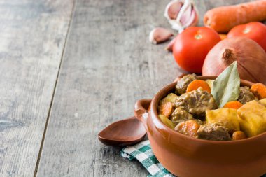 Patates, havuç ve baharat ahşap masa üzerinde seramik kase Komposto sığır eti