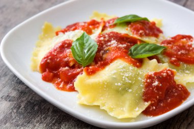 Domates sosu ve ahşap masa üzerinde fesleğen ile mantı