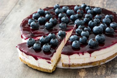 ahşap masa üzerinde yaban mersinli cheesecake