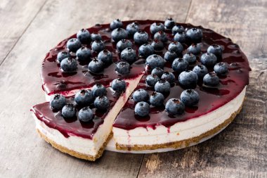 ahşap masa üzerinde yaban mersinli cheesecake