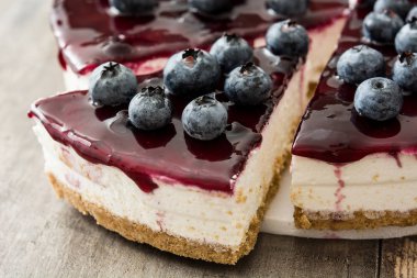 ahşap masa üzerinde yaban mersinli cheesecake