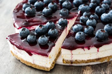 ahşap masa üzerinde yaban mersinli cheesecake