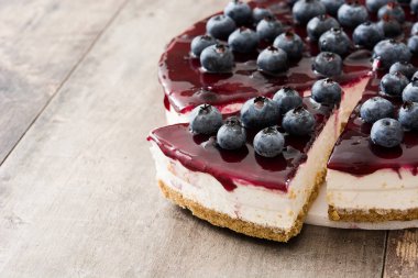 ahşap masa üzerinde yaban mersinli cheesecake