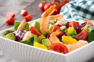 Mango ve ahşap masa üzerinde avokado karides salatası