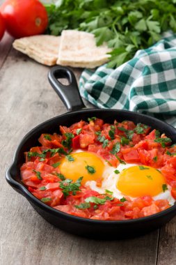 Ahşap masa üzerinde demir tavada Shakshuka. İsrail geleneksel yemekler.