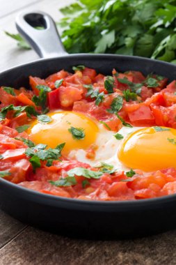 Ahşap masa üzerinde demir tavada Shakshuka. İsrail geleneksel yemekler.