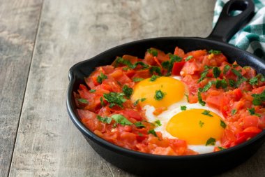 Ahşap masa üzerinde demir tavada Shakshuka. İsrail geleneksel yemekler.