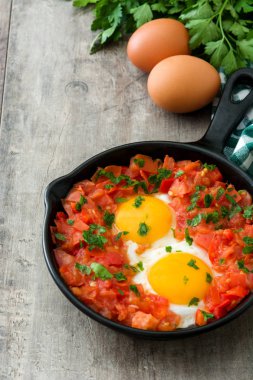 Ahşap masa üzerinde demir tavada Shakshuka. İsrail geleneksel yemekler.