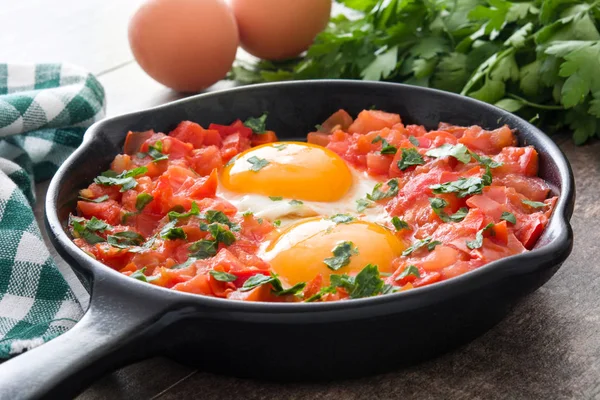 Shakshuka у Залізний сковороді на дерев'яний стіл. Типові страви в Ізраїлі. — стокове фото