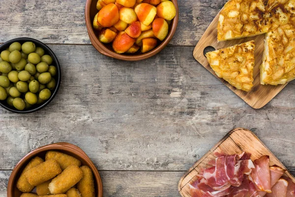 Tapas tradicionales españolas. Croquetas, aceitunas, tortilla, jamón y patatas bravas sobre mesa de madera — Foto de Stock