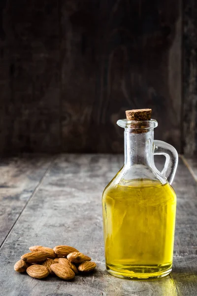 Миндальное масло в бутылке на деревянном столе — стоковое фото