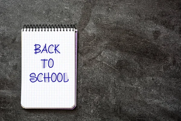 "Mensaje de regreso a la escuela escrito en un cuaderno sobre fondo de pizarra. Espacio de copia . — Foto de Stock