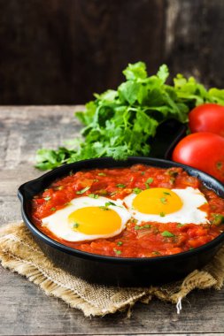 Meksika Kahvaltı: Huevos rancheros demir tavada ahşap tablo
