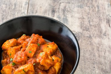 Tavuk tikka masala ahşap masa üzerinde siyah kase