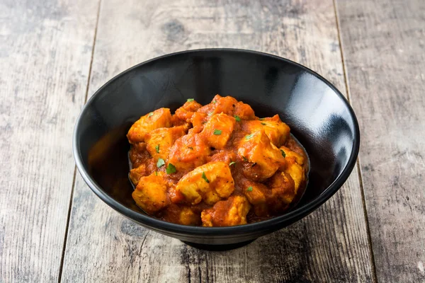Tavuk tikka masala ahşap masa üzerinde siyah kase