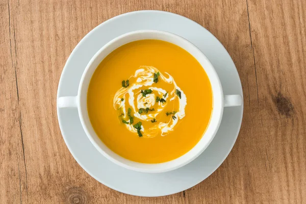 Sopa de abóbora em tigela branca na mesa de madeira — Fotografia de Stock