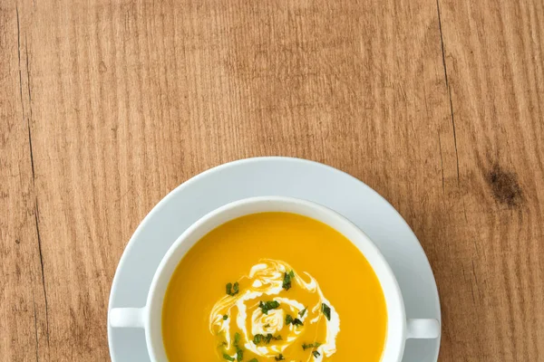 ahşap masa üzerinde beyaz kase kabak çorbası