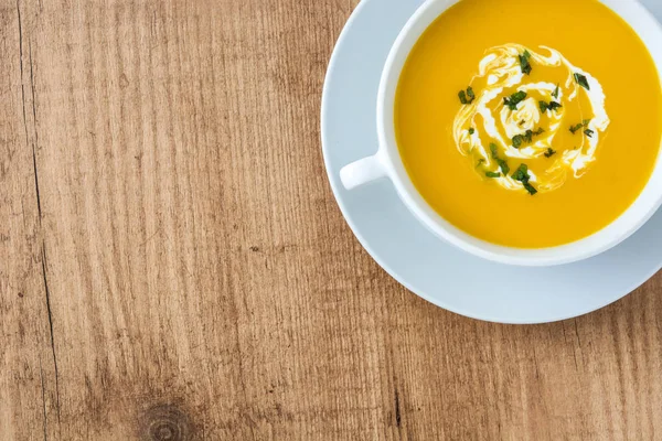 ahşap masa üzerinde beyaz kase kabak çorbası