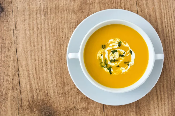 Sopa de abóbora em tigela branca na mesa de madeira — Fotografia de Stock