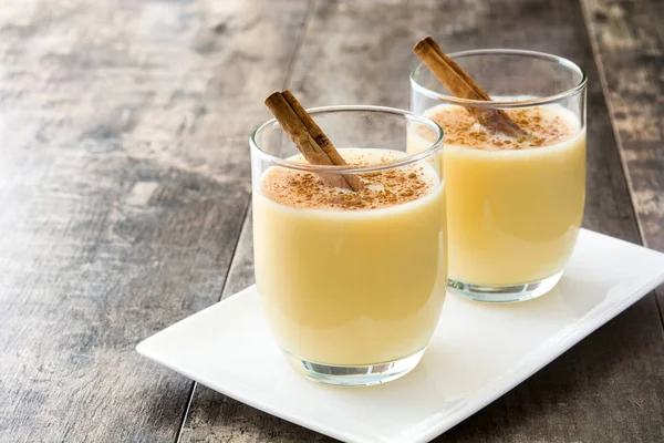 Tarçın ahşap masa üzerinde ev yapımı yumurta likörü. Tipik Noel tatlısı.