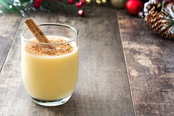 Tarçın ahşap masa üzerinde ev yapımı yumurta likörü. Tipik Noel tatlısı.