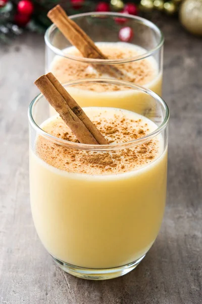 Tarçın ahşap masa üzerinde ev yapımı yumurta likörü. Tipik Noel tatlısı.