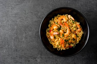 Erişte ve siyah taş üzerinde siyah kase sebzeli karides