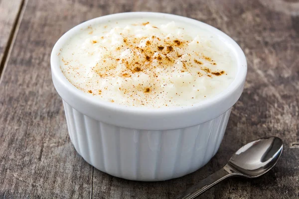 Arroz con leche. Budincă de orez cu scorțișoară pe fundal din lemn — Fotografie, imagine de stoc