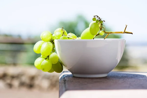 Raisins verts dans un bol blanc sur fond de champ — Photo