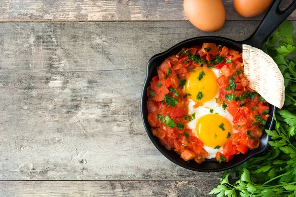 Shakshuka na panela de ato de fritar de ferro na mesa de madeira. Comida típica em Israel . — Fotografia de Stock