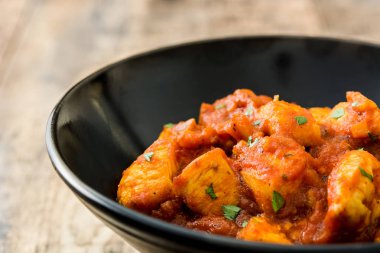 Tavuk tikka masala ahşap masa üzerinde siyah kase