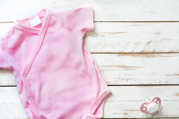 Ροζ baby romper μωρών σε άσπρο φόντο ξύλινη. Copyspace. — Φωτογραφία Αρχείου