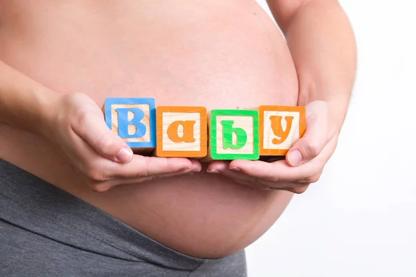 Mulher grávida segurando palavra bebê — Fotografia de Stock