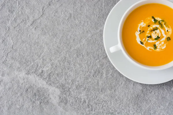 Gri taş üzerinde beyaz kase kabak çorbası