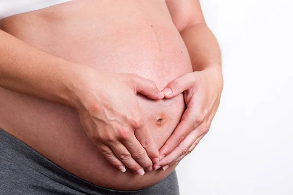 Mulher grávida segurando as mãos em forma de coração — Fotografia de Stock