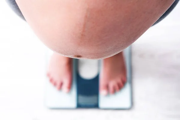 Беременная женщина стоит на весах — стоковое фото