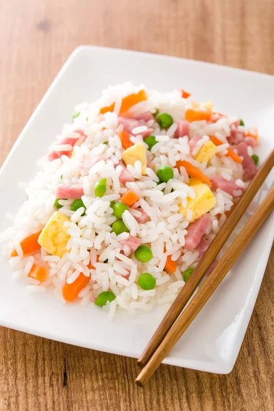 Жареный рис с овощами и омлетом на деревянном столе — стоковое фото
