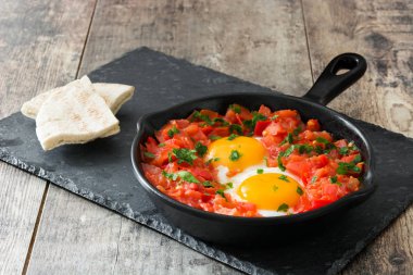 Ahşap masa üzerinde demir tavada Shakshuka. İsrail geleneksel yemekler.