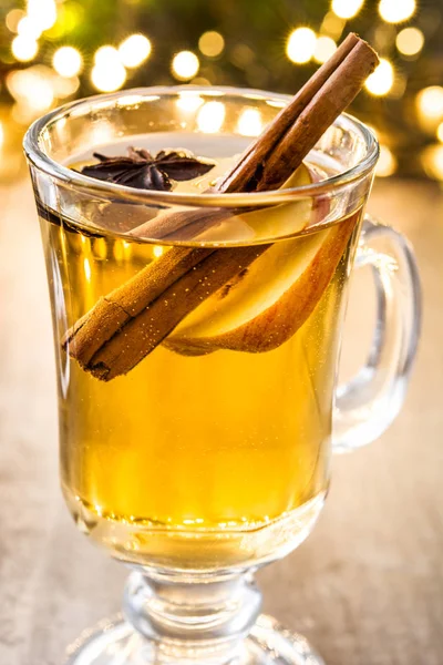 Sidra caliente en vidrio, adornos y luz de Navidad en mesa de madera — Foto de Stock