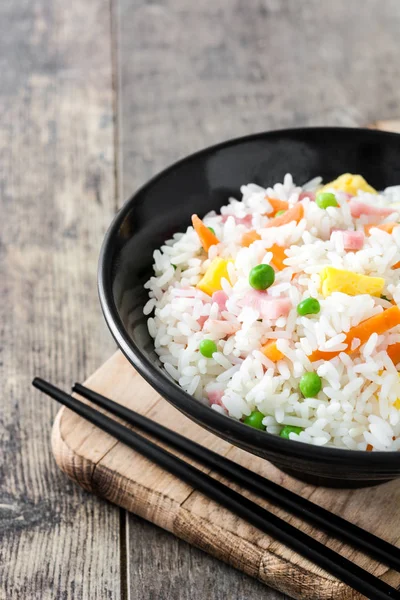 Жареный рис с овощами и омлетом на деревянном столе — стоковое фото