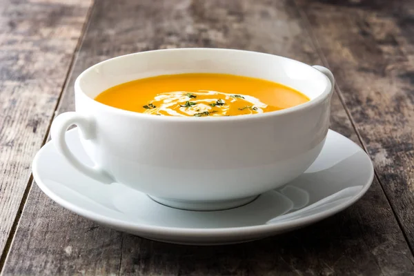 Гарбузовий суп у білій мисці на дерев'яному столі — стокове фото