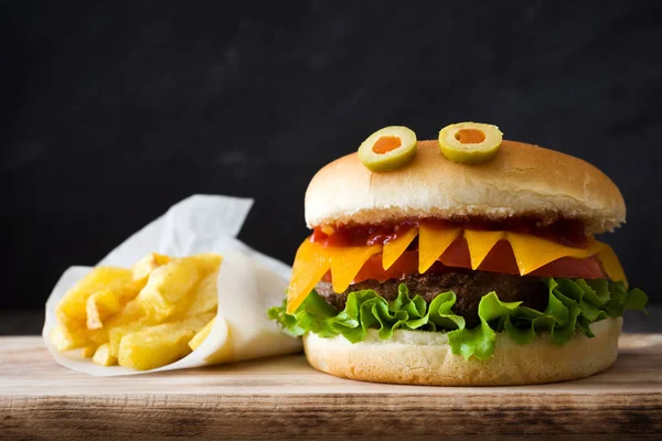 Halloween burger monsters with french fries on wooden table — Stock Photo, Image