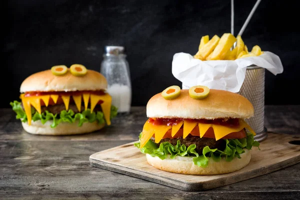 Halloween burger monsters with french fries on wooden table — Stock Photo, Image