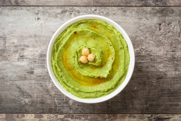 Hummus de aguacate en cuenco sobre mesa de madera.Vista superior —  Fotos de Stock