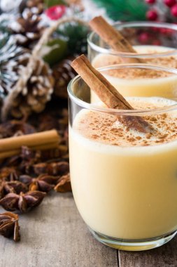 Tarçın ahşap masa üzerinde ev yapımı yumurta likörü. Tipik Noel tatlısı.