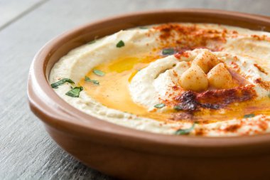 Ahşap masa üzerinde bir kapta nohut humus.