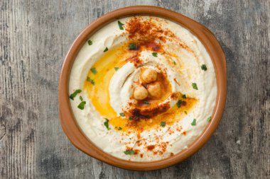 Ahşap masa üzerinde bir kapta nohut humus.