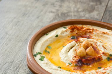 Ahşap masa üzerinde bir kapta nohut humus.